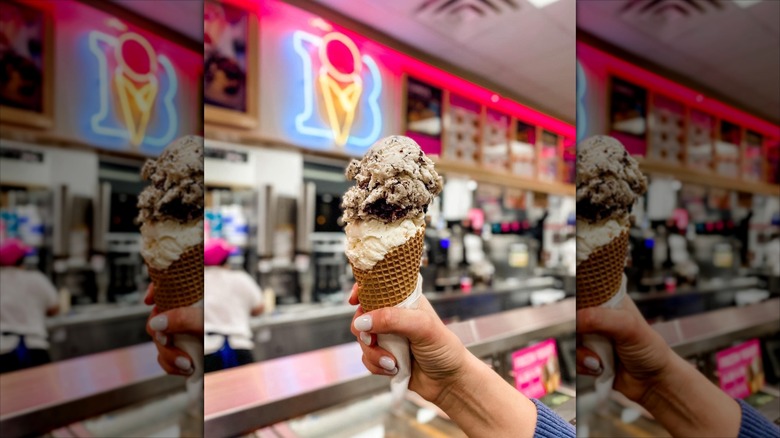 Woman holding a Double scoop Braum's Ice Cream Cone in ice cream shop with Braum's neon logo in background