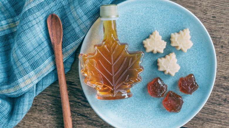 Maple Candies on plate beside Maple Syrup and wooden spoon with blue cloth