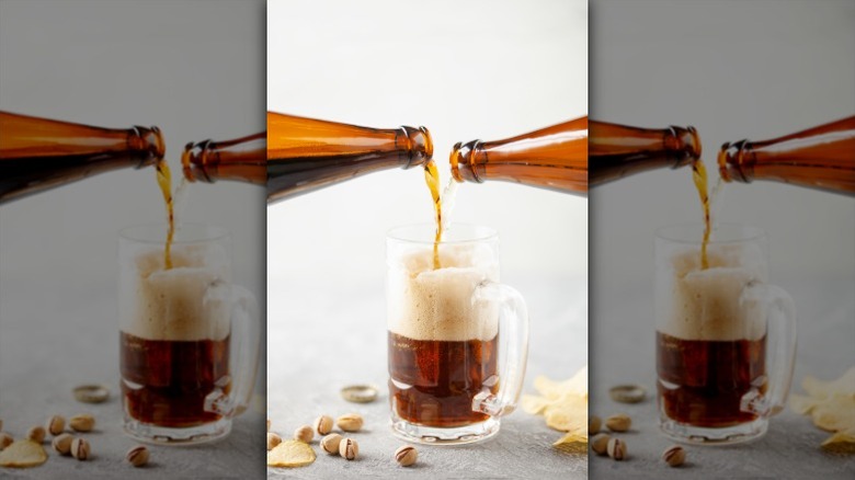 Two bottles of beer are poured into a pint mug to create a Black and Tan