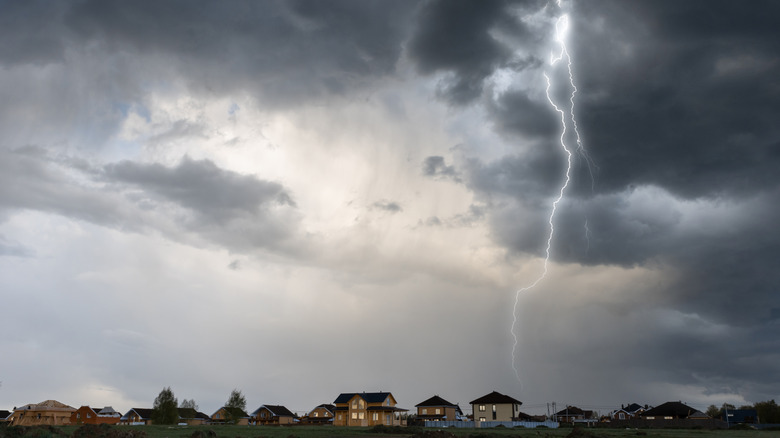 Lightning strike over homes under a grey sky