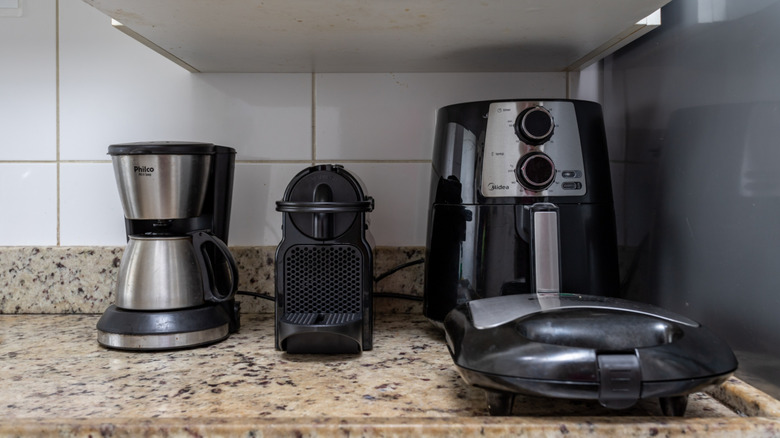 Two coffee makers, an air fryer, and a toastie maker on a kitchen counter