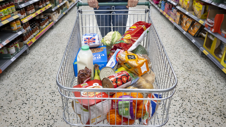 Person pushing shopping car filled with groceries
