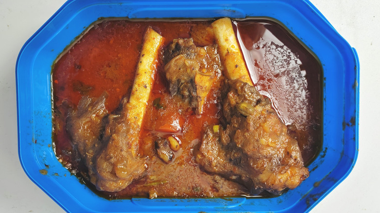 A blue bowl of mutton bones in a red sauce