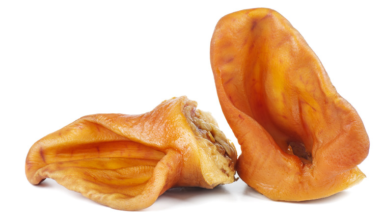 Two chopped pig ears against a white background