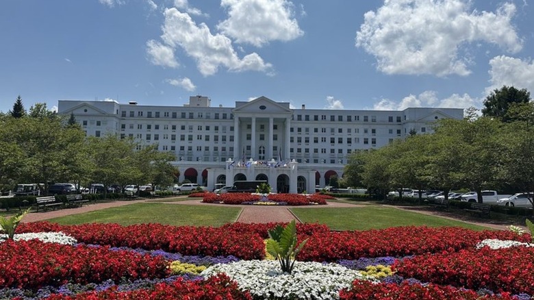 The exterior of the Greenbrier resort; large white grand Georgian Revival building with well-tended gardens and lawn in the front