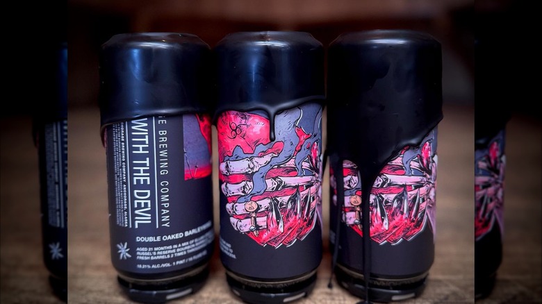 Three cans of A Deal with the Devil on a wooden table