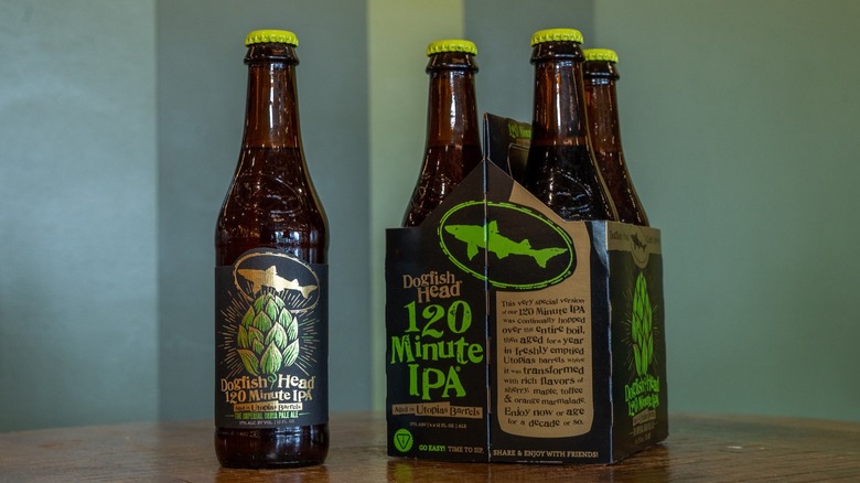 A bottle of Dogfish Head 120 Minute IPA next to three other bottles in a cardboard four pack