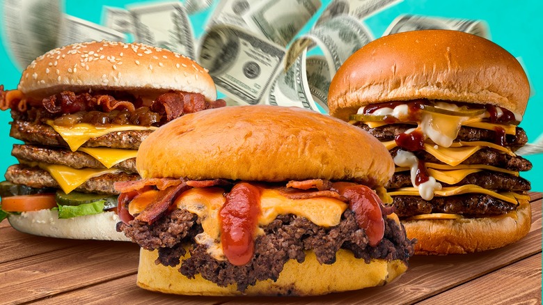 Three big burgers with cash behind them