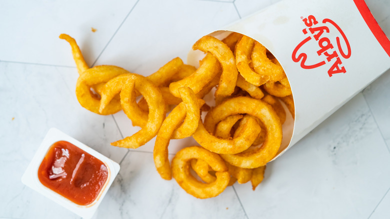 arby's curly fries with ketchup on white table