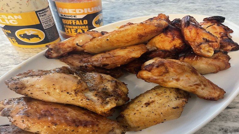 buffalo wild wings on a white plate with bottled sauces in background