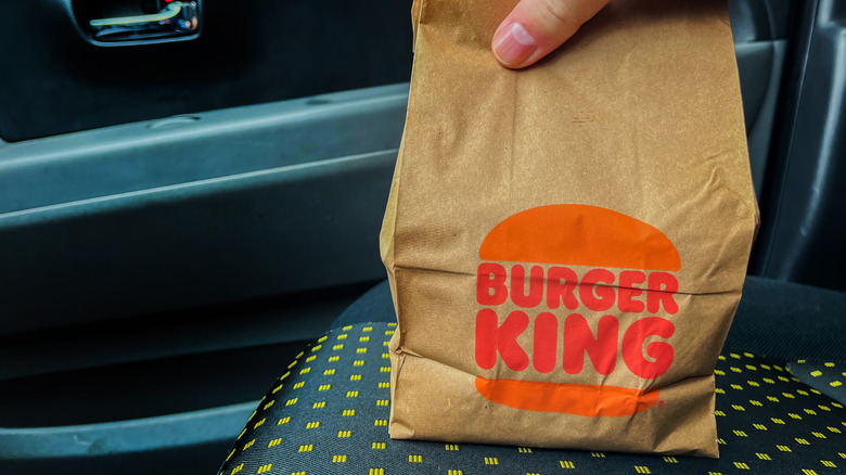 person holding a burger king bag on a seat