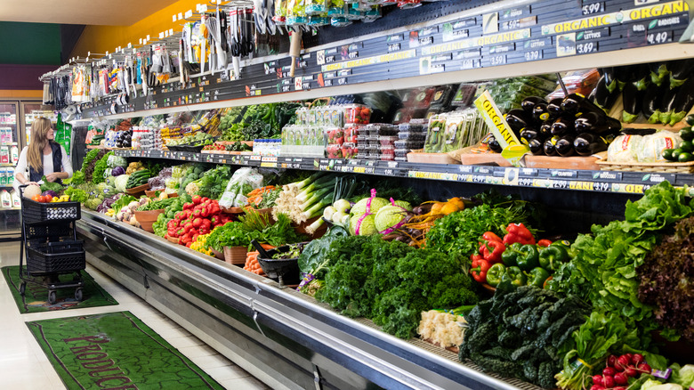 Woman with shopping cart browses refrigerated produce at Trader Joe's