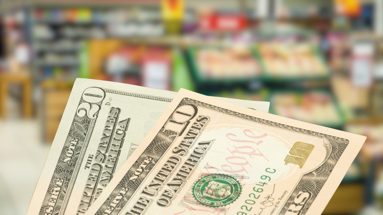 Dollar bills against blurred background of grocery store