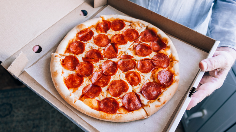 man holding open a box of pizza