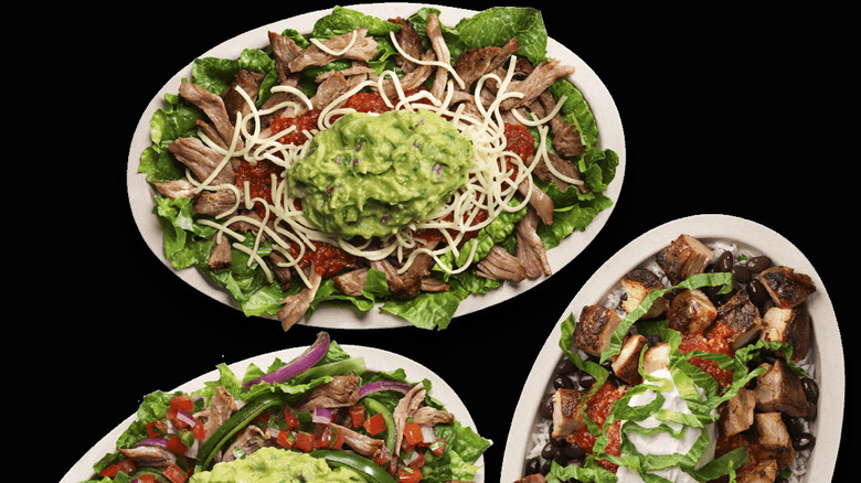 Three Chipotle bowls on a black background.