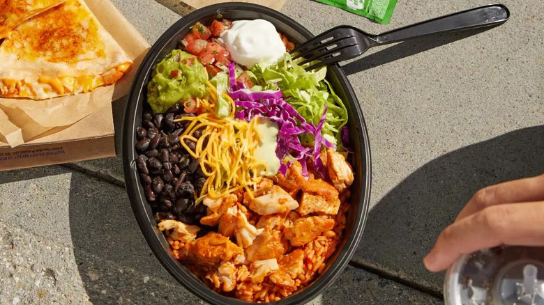 Cantina Chicken Bowl with fork, a quesadilla, and a hand