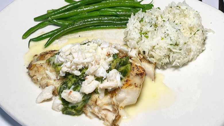 A plate of Bonefish Grill Rockefeller Butterfish next to a side of rice and green beans.