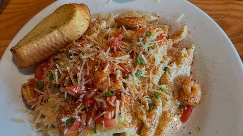 A plate of Chili's Cajun Shrimp Pasta with garlic bread.