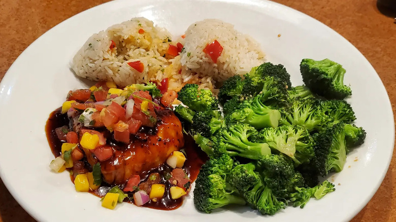 A plate of TGI Fridays Dragon Glazed Salmon, with a side of rice and broccoli.