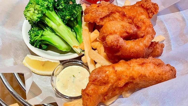 A plate of Fish and Chips from Cheesecake Factory with a side of broccoli.