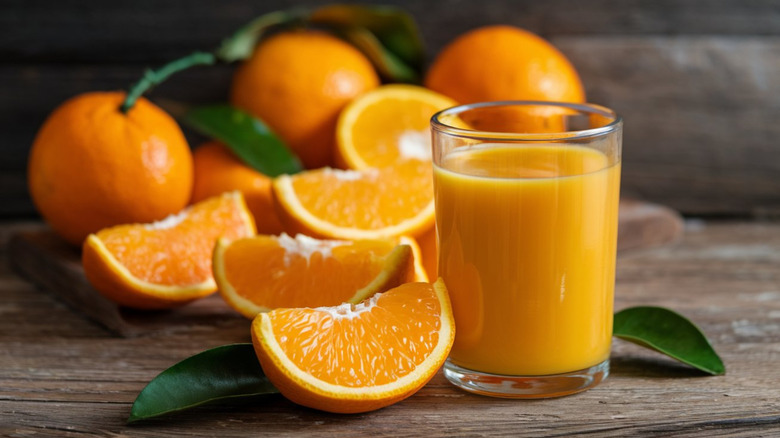 A glass of orange juice with fresh orange wedges