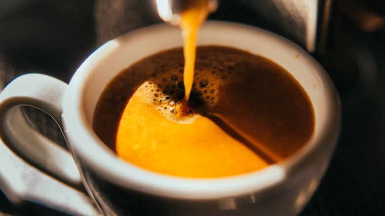 Coffee pours into a white mug