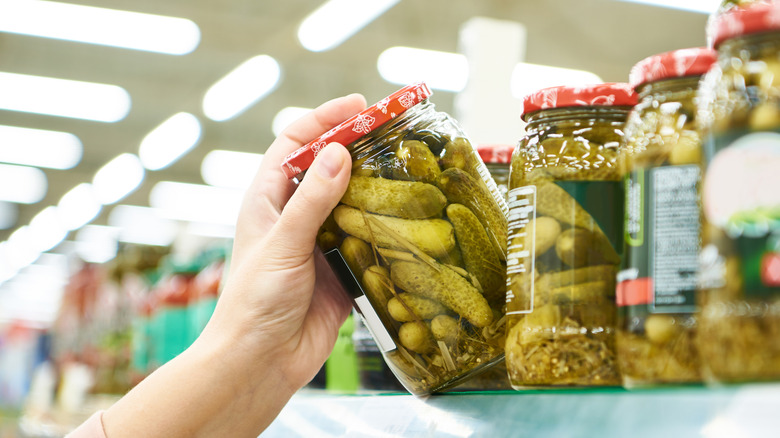 Hand grabbing pickle jar off store shelf