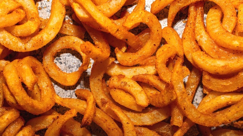 Curly fries laid out on a metal tray.