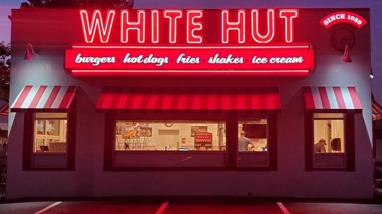 Exterior of White Hut with neon sign and iconic red and white striped awnings