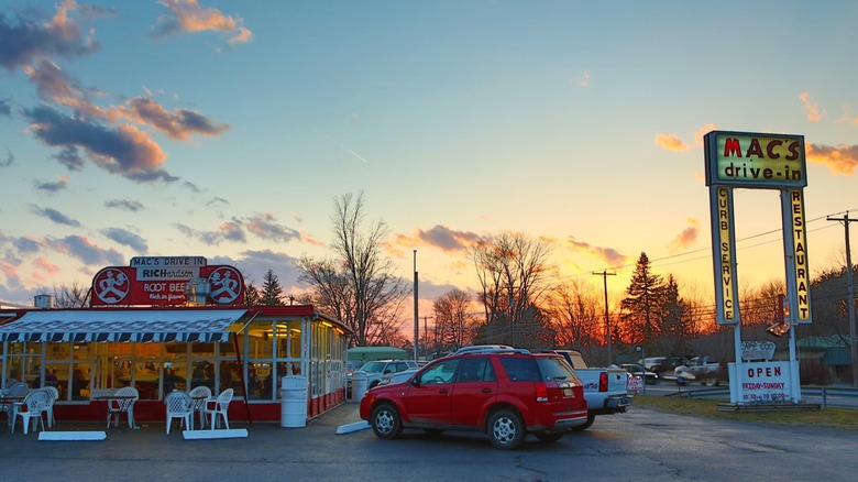 Exterior of Mac's Drive In showing cars and roadside sign