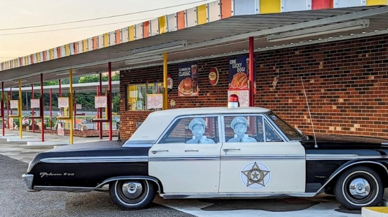Exterior of Mayberry Drive In with vintage car and cardboard cutouts of Barney Fife