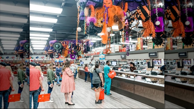 Customers line up inside warehouse candy store with Halloween decor