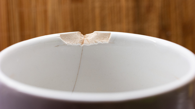 A ceramic mug with a chipped rim sitting on a table.