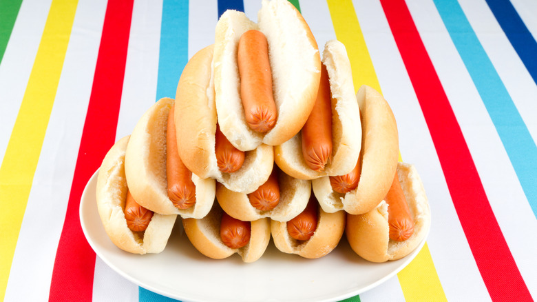 A plate piled with hot dogs atop a colored background
