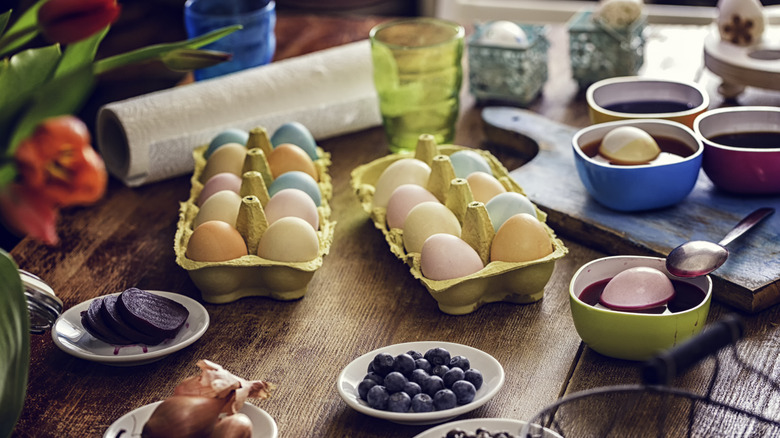 Dyed eggs surrounded by assorted natural dyes, fruits, and vegetables