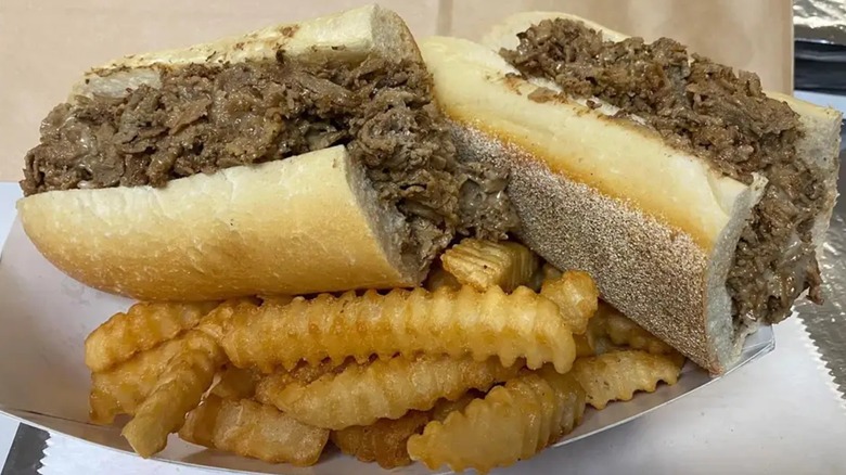 A cheesesteak from Roman Pantry cut in halves on a bed of French fries