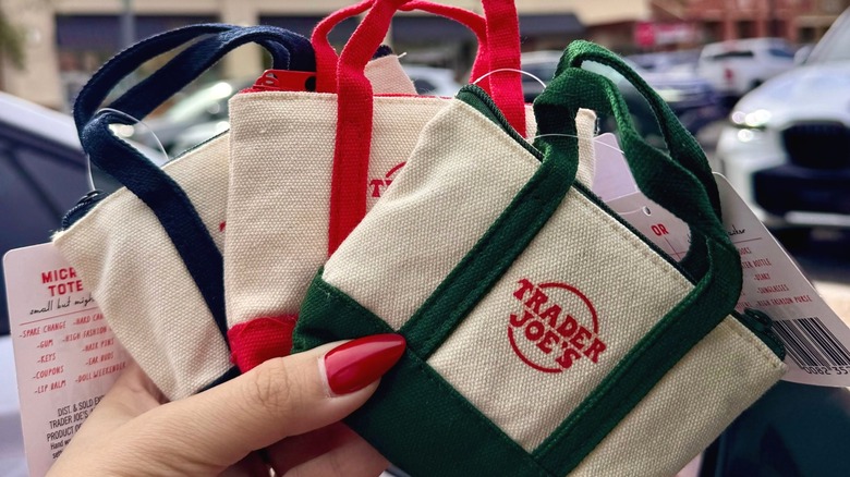 Person holding three Trader Joe's mini totes in three colors