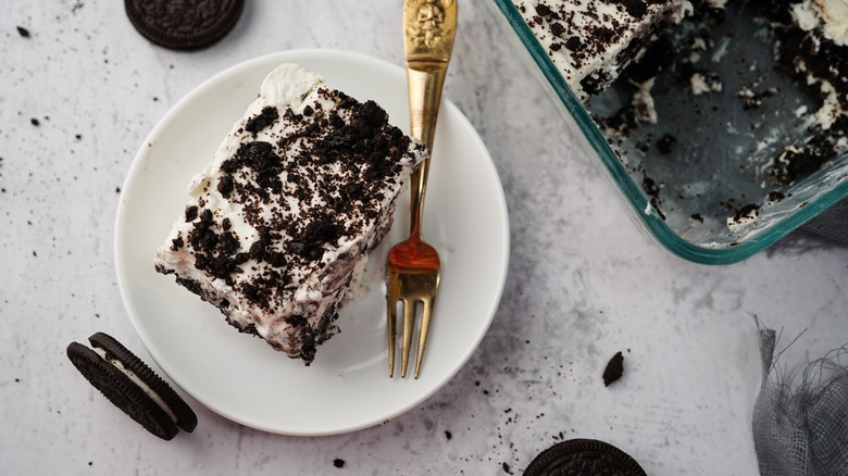 Oreo icebox cake piece dusted with chocolate crumbs on a plate with a gold fork
