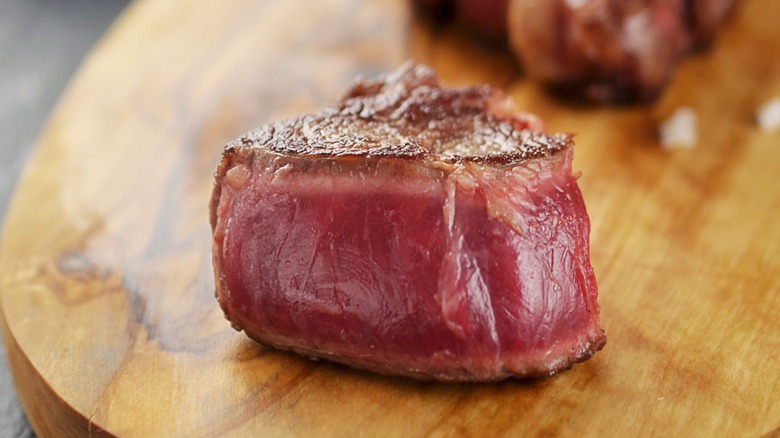 Piece of blue rare steak on wood board