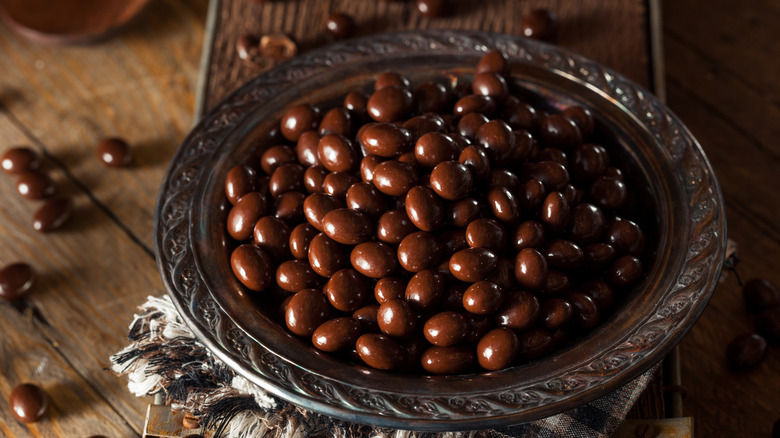 Chocolate-covered espresso beans in a silver bowl on a wooden table