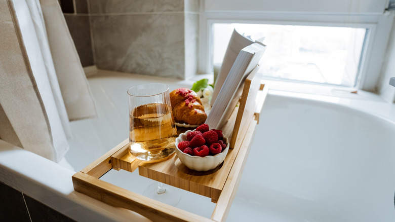 Breakfast and a book on a tray over a bathtub