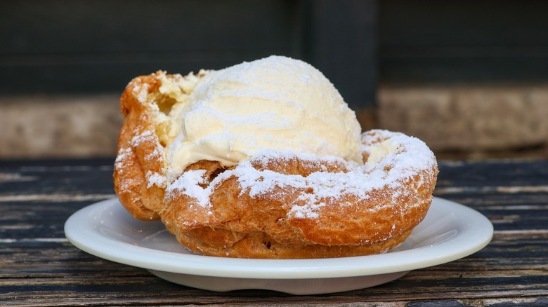 A cream puff pastry filled with whipped cream and dusted with powdered sugar on a white plate