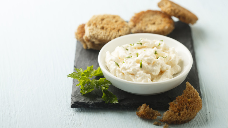 A small bowl of shrimp dip on a black plate with toasted bread on the side