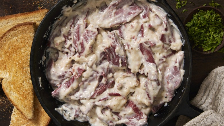 Creamed chipped beef in a pan next to slices of toast