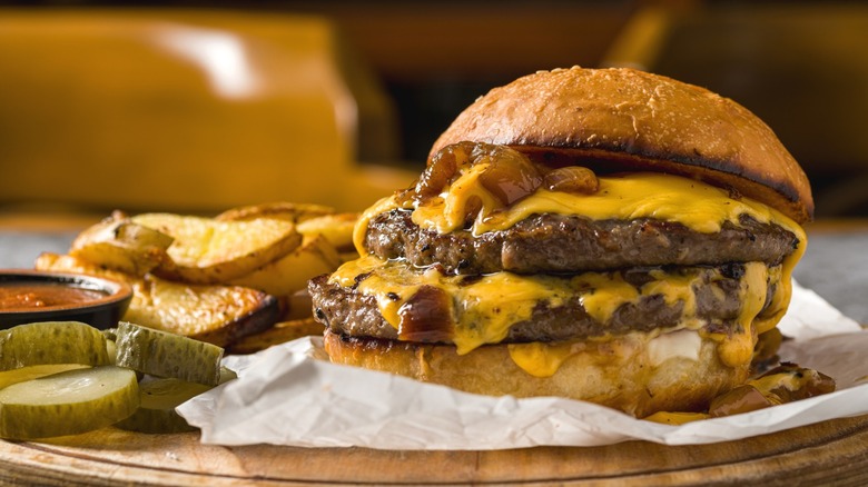 A cheeseburger with french fries and pickles.