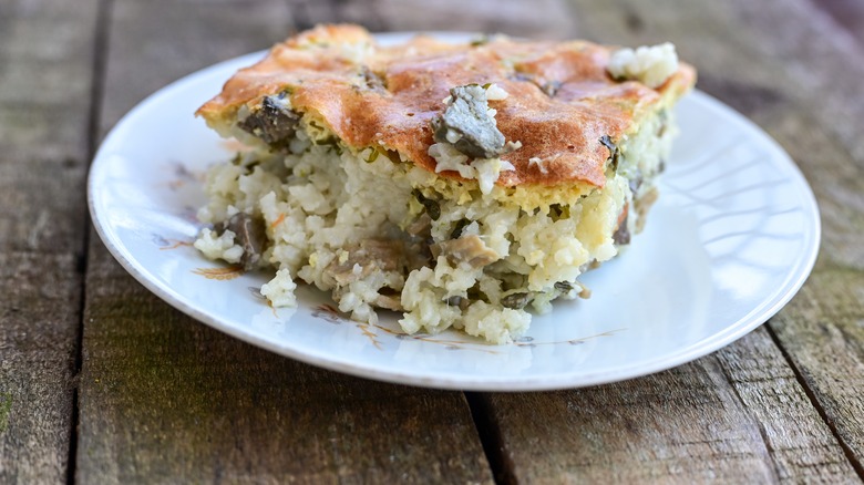 Serving of cheese and rice casserole with additional ingredients on small white plate.
