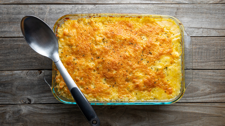 Baked cheese and rice casserole in a glass baking dish with serving spoon.