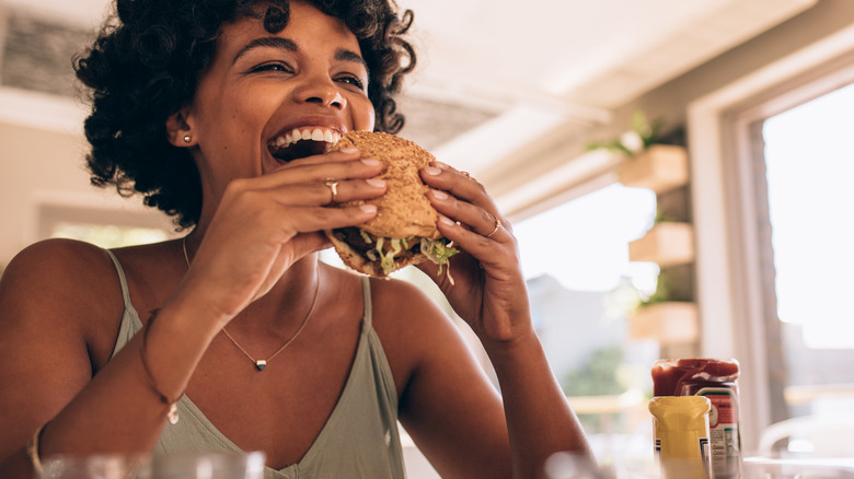 A woman eats a burger inside a modern restaurant