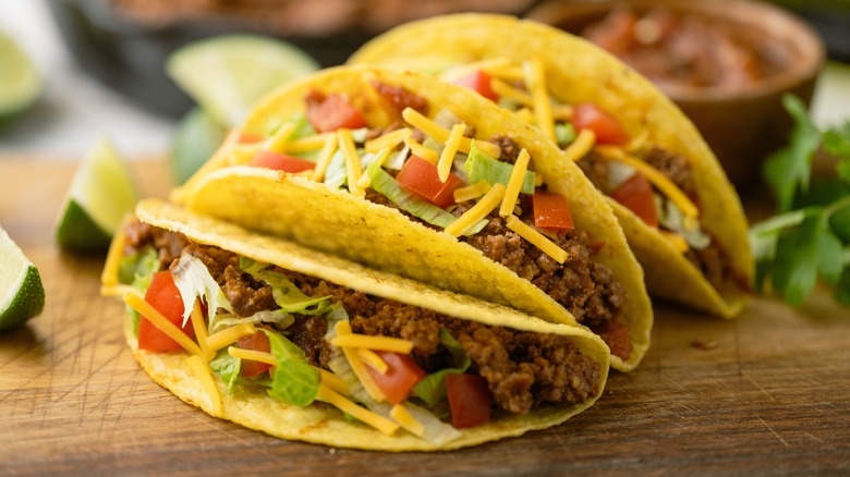 crunchy beef tacos with shredded cheese, lettuce, and tomato