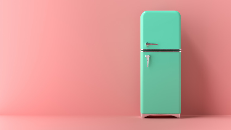 A retro turquoise refrigerator on a pink background